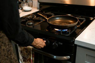 A person uses a non-stick pan on a gas stovetop